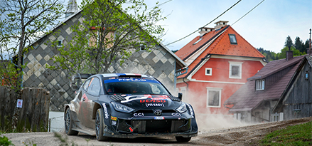 Voiture de course Toyota roulant sur une piste en graviers surplombée par des rochers