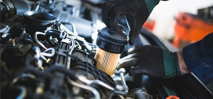 Une main retire le filtre à huile du moteur