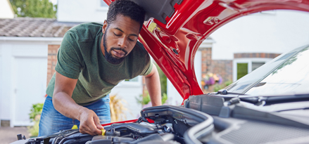 Une personne répare sa voiture avec le capot relevé