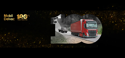 Voiture ancienne suivant un camion rouge moderne sur une autoroute avec des étincelles dorées